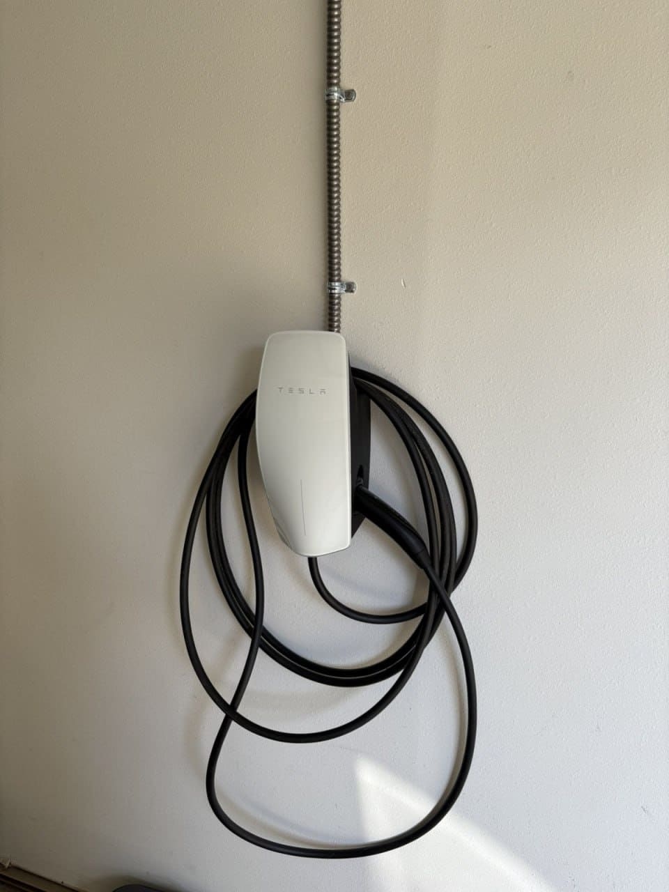 Borne Tesla fixée sur un mur intérieur avec câble enroulé
